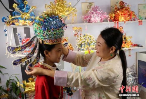 图为王媛娇给女儿戴上凤冠。夏晓婷 摄