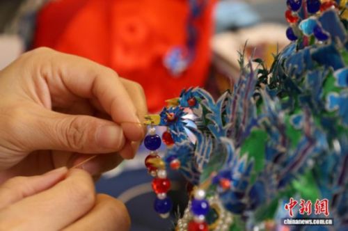 图为王媛娇在给凤冠缝制吊坠。夏晓婷 摄