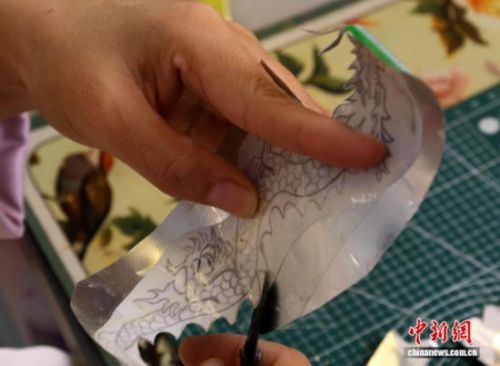 图为王媛娇按照图纸裁剪易拉罐。夏晓婷 摄