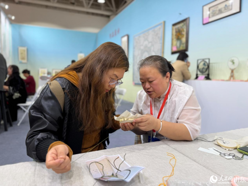 观展人在技艺体验区体验刺绣。人民网记者 乔姝摄